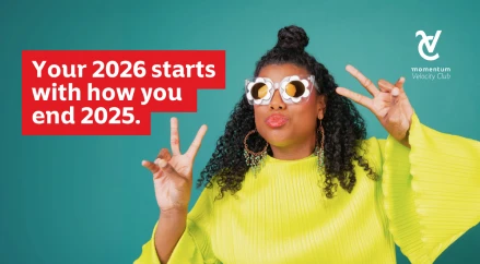 A young woman wearing retro-style glasses and a bright green shirt, smiling and flashing peace signs, representing optimism, confidence, and a fresh start for the new year.